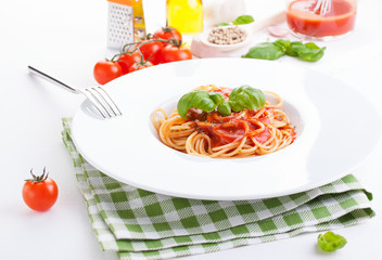 Tomato pasta spaghetti with fresh tomatoes, basil, italian herbs and olive oil in a white bowl on a white wooden background, closeup