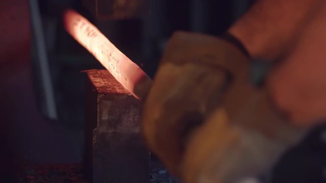 Hot metal being worked by a blacksmith with a large industrial hammer.  Detail shot, originally recorded in 4K at 60fps.