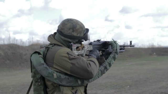 A soldier with a machine gun on a military firing range shooting at a target.