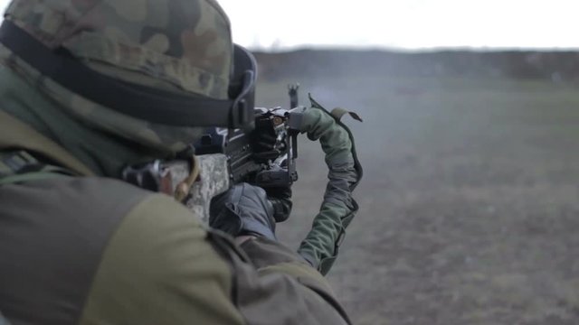 A soldier with a machine gun on a military firing range shooting at a target.