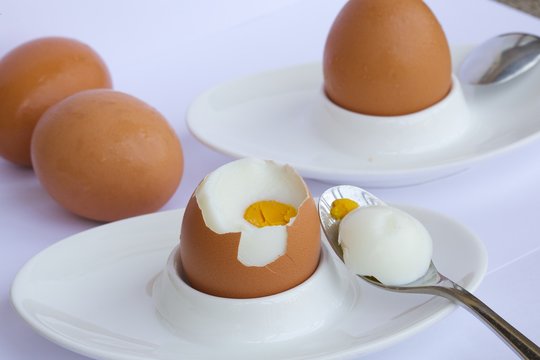 Peeled egg on a white egg holder.