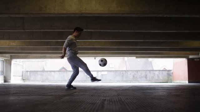 Football player doing kick up tricks in an urban city environment