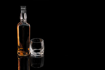 Bottle whiskey and empty glass on black background
