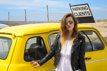Young Hippie girl standing next to an old vintage, retro car