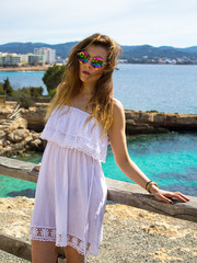 Cute hippie girl standing on a cliff by the sea