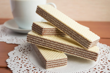 Crunchy chocolate wafers on white napkin and cup of coffee.