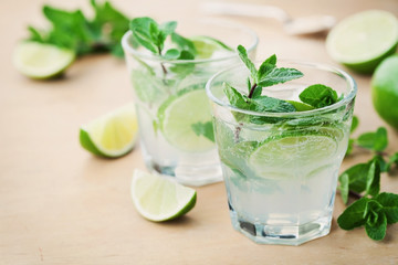 Mojito cocktail with lime, ice and mint leaves on wooden table, popular summer drink
