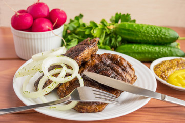 Pork steak, grilled with onion rings and fresh vegetables, herbs