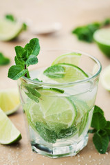 Mojito cocktail with lime, ice and mint leaves on wooden table, popular summer drink