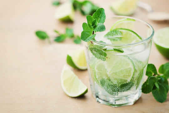 Mojito cocktail with lime, ice and mint leaves on wooden table, popular summer drink