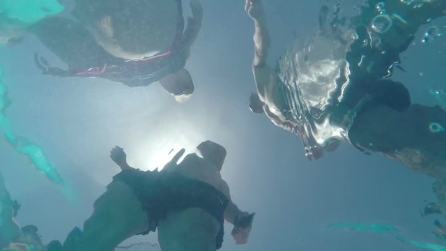 Underwater slow motion view of people through the water surface.