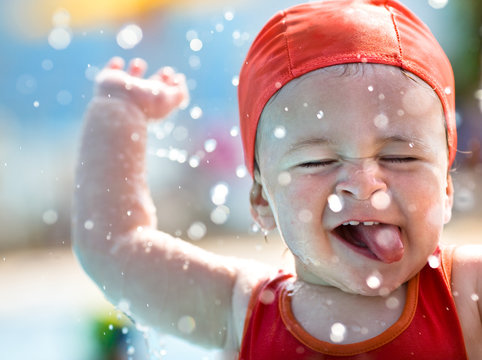 cute happy child playing with water and bubbles at swimming pool during summer
