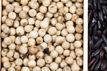 Spices and black rice in a wooden box: red, green and white pepper, sea salt, himalayan salt, allspice and coriander