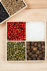 Spices and black rice in a wooden box: red, green and white pepper, sea salt, himalayan salt, allspice and coriander
