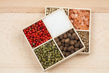 Spices and black rice in a wooden box: red, green and white pepper, sea salt, himalayan salt, allspice and coriander
