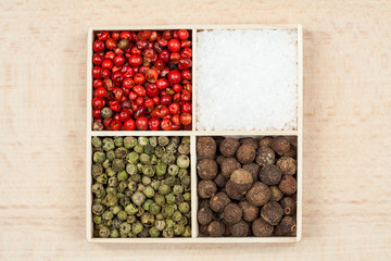 Spices and black rice in a wooden box: red, green and white pepper, sea salt, himalayan salt, allspice and coriander