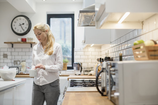 A woman making a cup of tea in a modern kitchen. 