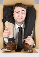 flexible businessman with doubtful smiling face in a cardboard box