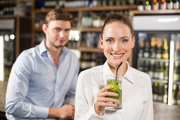 Woman drinking beverage in front of man