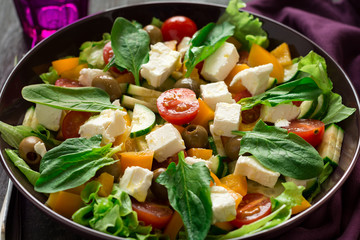 Fresh greek salad with Feta and vegetables on purple plate