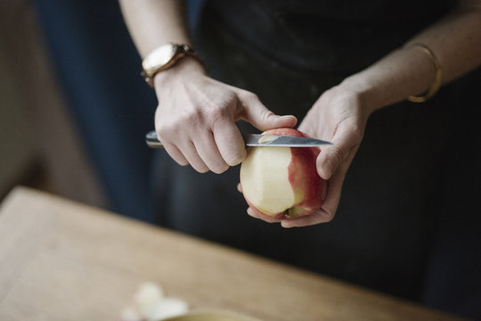 A woman peeling an apple with a knife