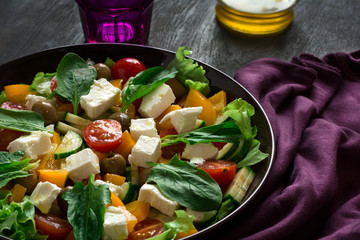 Fresh greek salad with Feta and vegetables on purple plate
