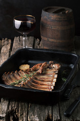 Grilled pork ribs on a dark pan with a glass of wine