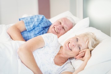 Fototapeta na wymiar Portrait of happy senior woman resting besides man on bed