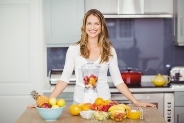 Portrait of cheerful woman standing at table