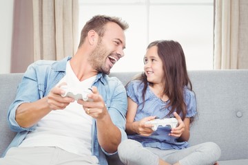 Fototapeta premium Smiling father and daughter playing video game 