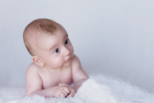 Newborn Naked Baby Curiously Observing Environment on a Soft Blanket
