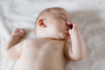 Newborn Naked Baby Sucking Thumb Finger at Bed Time Laying on Back on Blanket