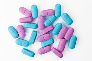 Pile of mixed colorful pink and blue pills on white background directly from above