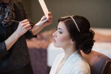 Woman with beautiful hairstyle doing makeup, boudoir