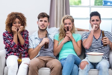 Nervous multi-ethnic friends watching TV at home