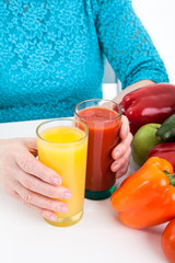 Fresh ecological, natural products: vegetables, fruits and fresh juices are in the arms of mature woman and on a table