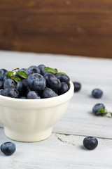 Ceramic bowl with fresh blueberries on a wooden background