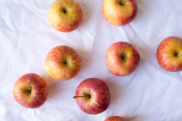 High angle view of natural looking red apples scattered on white tablecloth