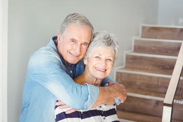 Portrait of cheerful senior couple embracing on staircase