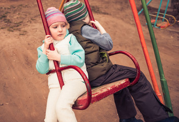 boy and girl riding on a swing