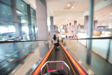 Blur image of people walking down the escalator at airport.