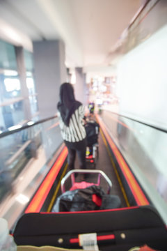 Blur image of people walking down the escalator at airport.