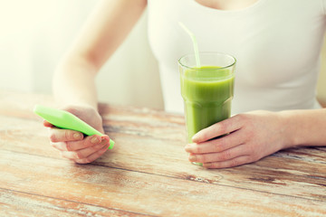 close up of woman with smartphone and green juice