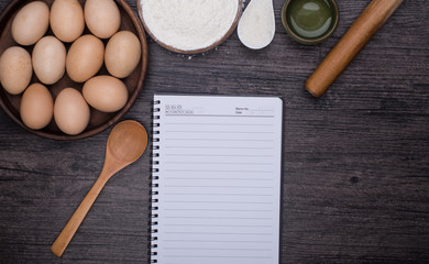 Wooden background with baking ingredients (eggs, flour and rolling pin) over rustic texture. Top view. Space for text. Food or cooking concept.