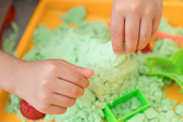 Close up of kid's hands playing sand in sandbox
