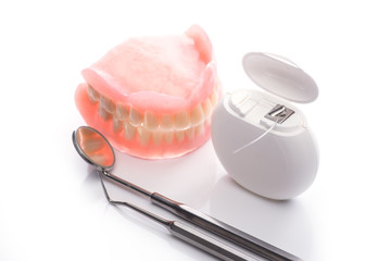 Teeth model with dental floss and mouth mirror on white background