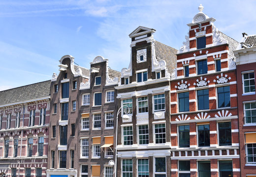 Old town houses of cobblestone with clear blue sky. Antique, traditional row houses in Amsterdam, the Netherlands.