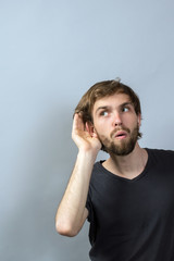 Headshot curious man listening to conversation news eavesdropping privacy concept isolated on grey wall background with copy space. Human face expression, reaction, emotion, life perception