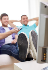 close up of happy male friends watching tv at home