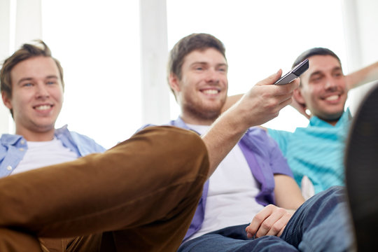 happy male friends with remote watching tv at home